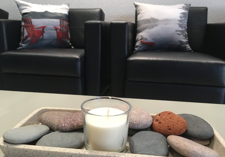 A candle set in river stones on the table in front of the waiting chairs