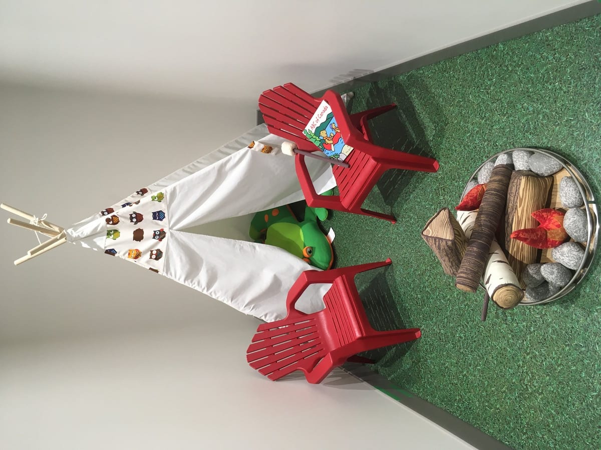The Kids Campground at Moose Lake Dental, with the teepee, the simulated fire pit and the red muskoka chairs